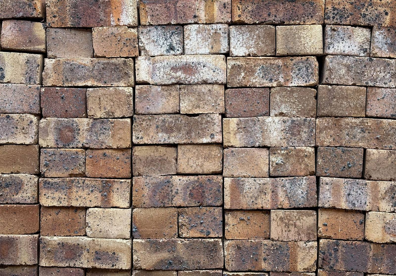 Weathered facing bricks stacked in tight courses on a pallet.