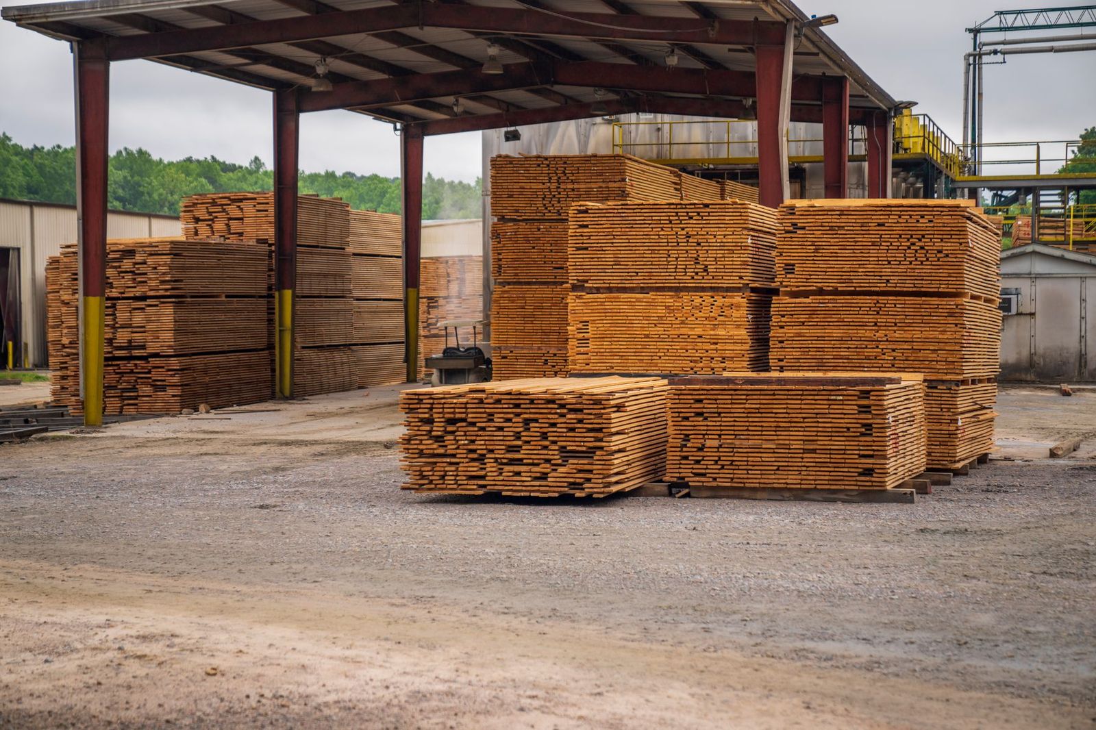 Stacked sawn timber under an open canopy in a timber yard.